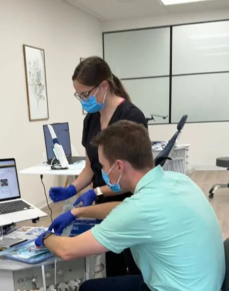 Two masked dental professionals work with equipment, possibly providing orthodontic services at Chauncey Orthodontics in Henderson, NV.