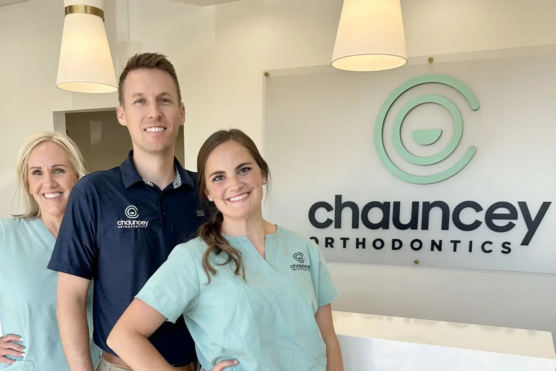 Staff at Chauncey Orthodontics in Henderson NV, pose in front of their logo, ready to welcome patients for orthodontic consultations.