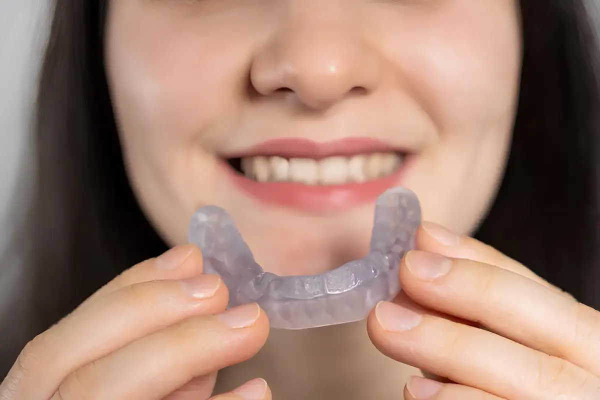 A woman holds dental mouth guard solution for protect her smile, recommended Chauncey Orthodontics in Henderson NV if need Best TMJ Mouthguard.