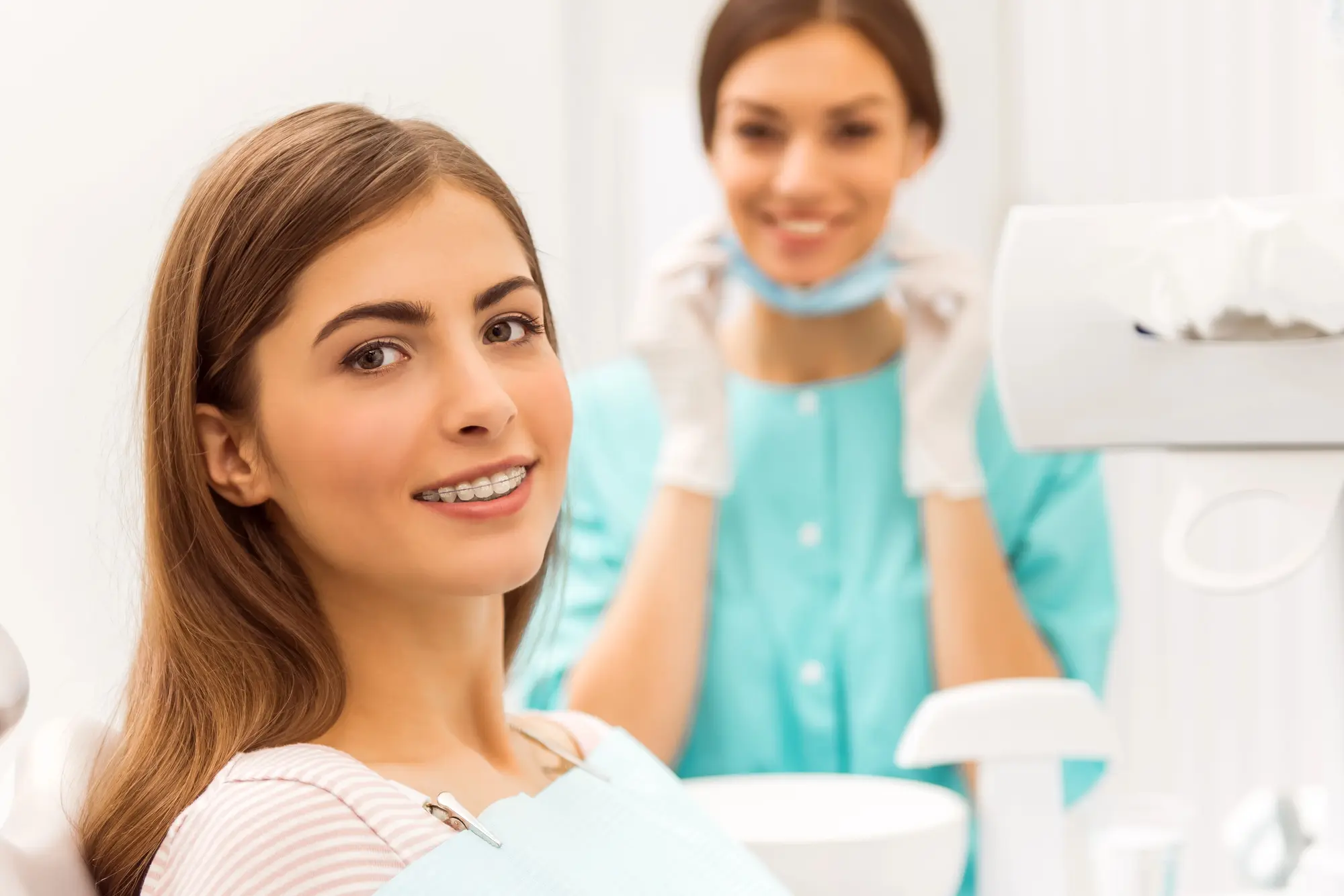 A young woman with braces sits in a dental chair, smiling representing best adult orthodontics at Chauncey Orthodontics in Henderson, NV.