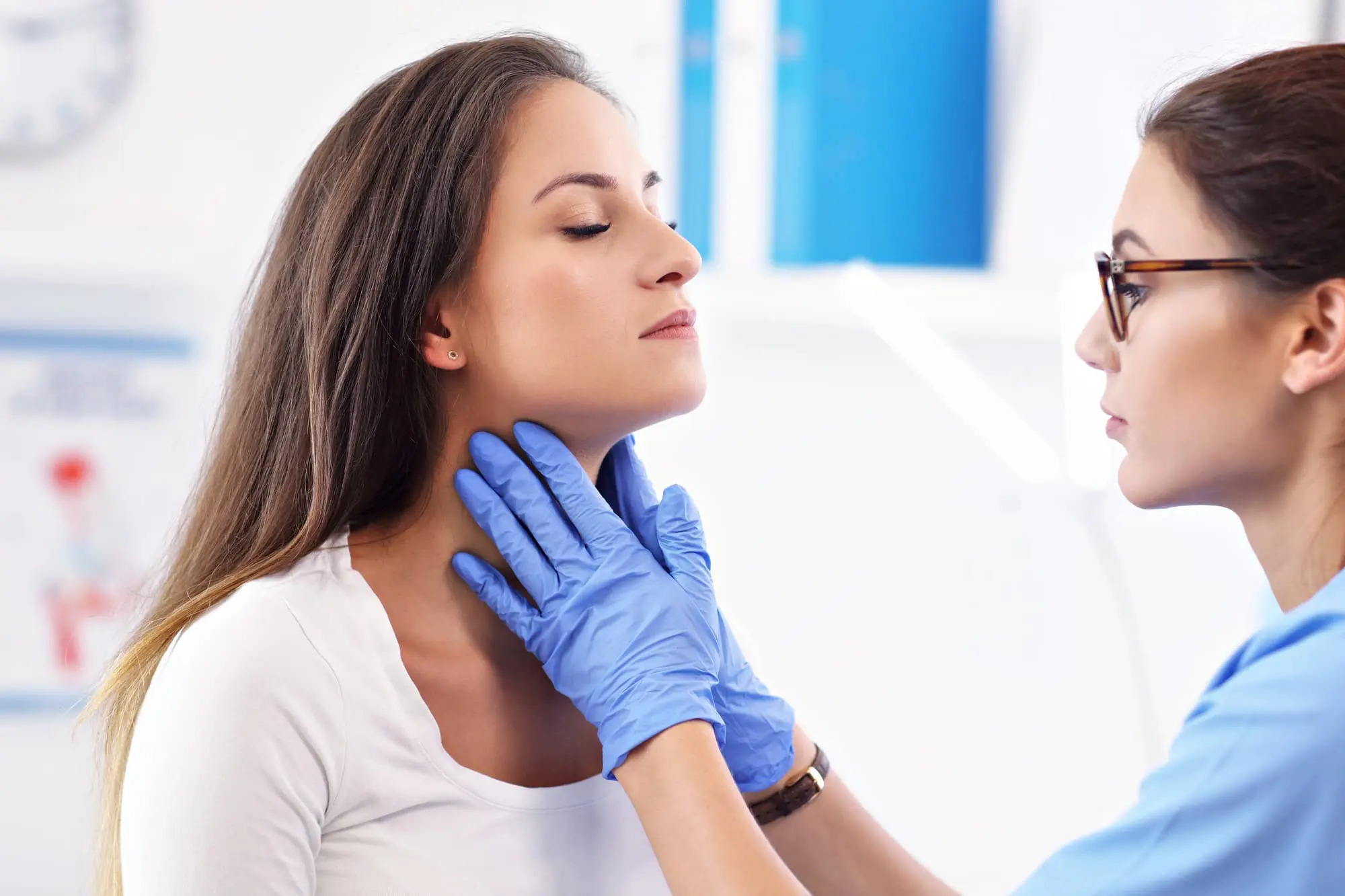 At Chauncey Orthodontics in Henderson NV, a woman doctor examines a woman's neck in a medical office setting. possibly considering jaw surgery.