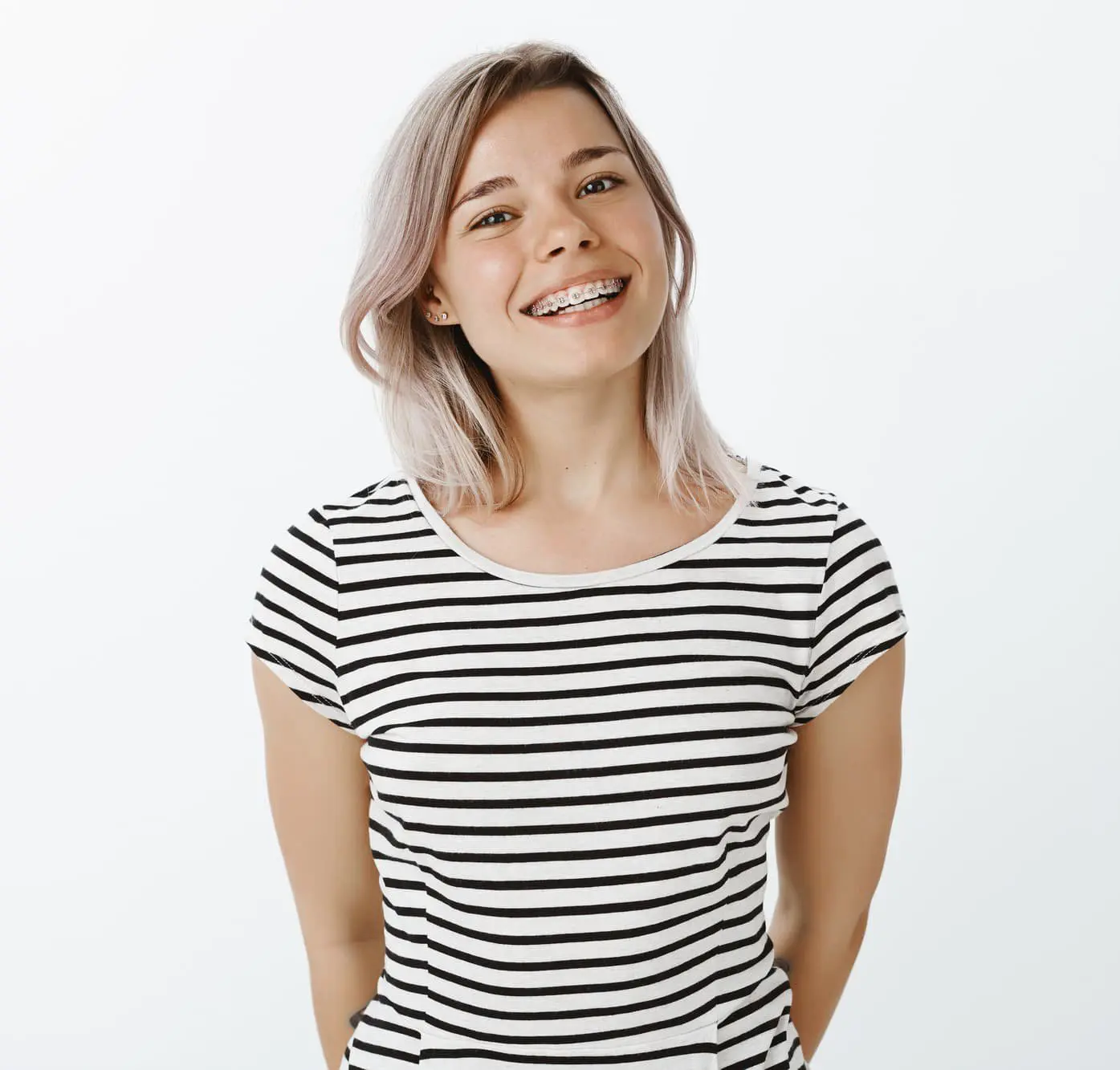 Young woman with light hair wearing a black and white striped shirt, smiling and showing metal braces example of the confident smiles created by Chauncey Orthodontics in Henderson, NV.