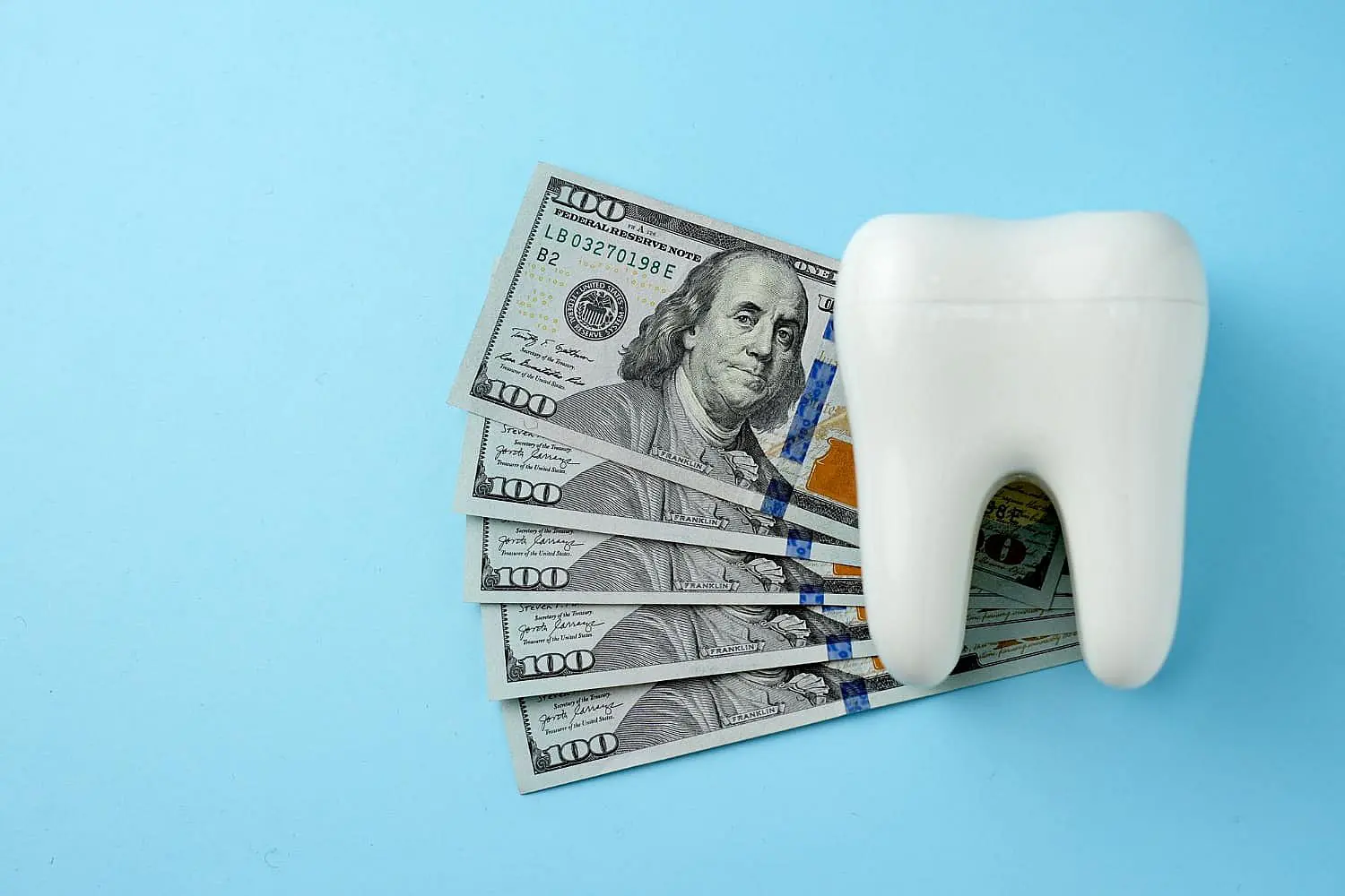 Beside a tooth-shaped object and five spread-out U.S. hundred-dollar bills on a light blue background, Chauncey Orthodontics in Henderson NV highlights the cost and insurance coverage considerations tied to orthodontic treatments.