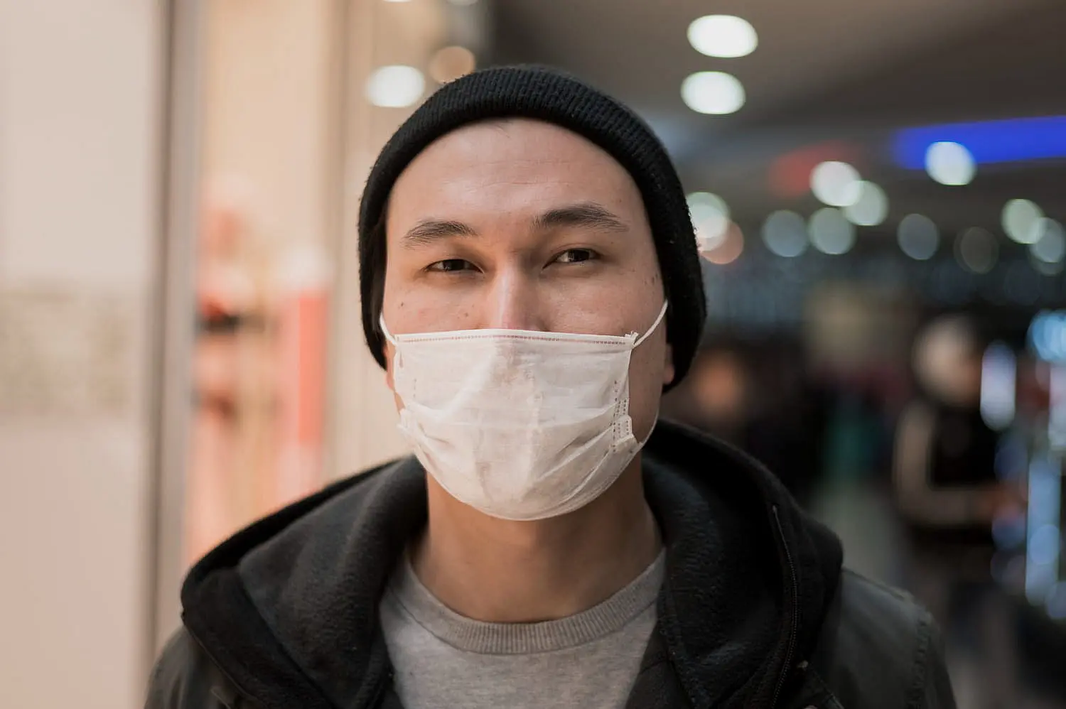 a person stands with a mouth breathing issue wearing a black beanie and white mask in Henderson, NV.