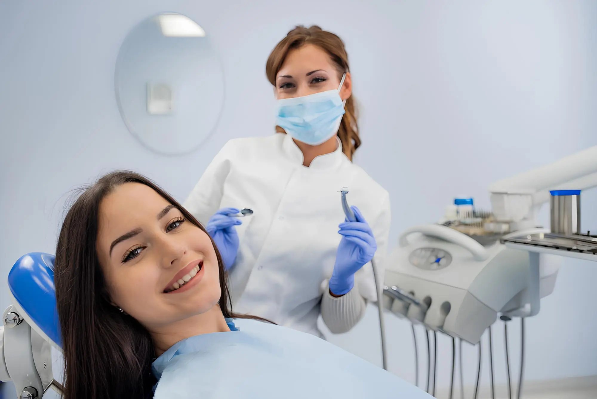 A woman sits in a dental chair smiling while a dentist in a mask for discussed overbite issues from patient at Chauncey Orthodontics
in Henderson, NV.