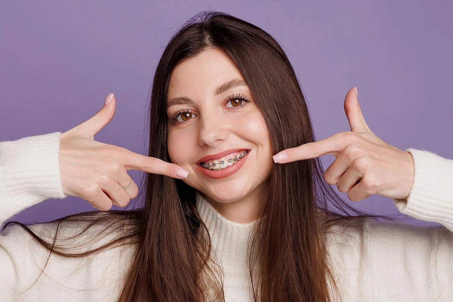 A woman highlighting their braces. This subtly points to the Invisalign vs Braces debate at Chauncey Orthodontics operates in Henderson, NV.