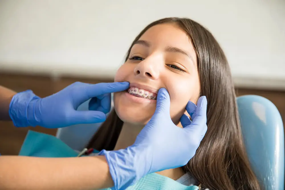 Best Orthodontics An orthodontist in blue gloves examines a young patient's braces. Contact Chauncey Orthodontics in Henderson, NV, for information on braces costs.