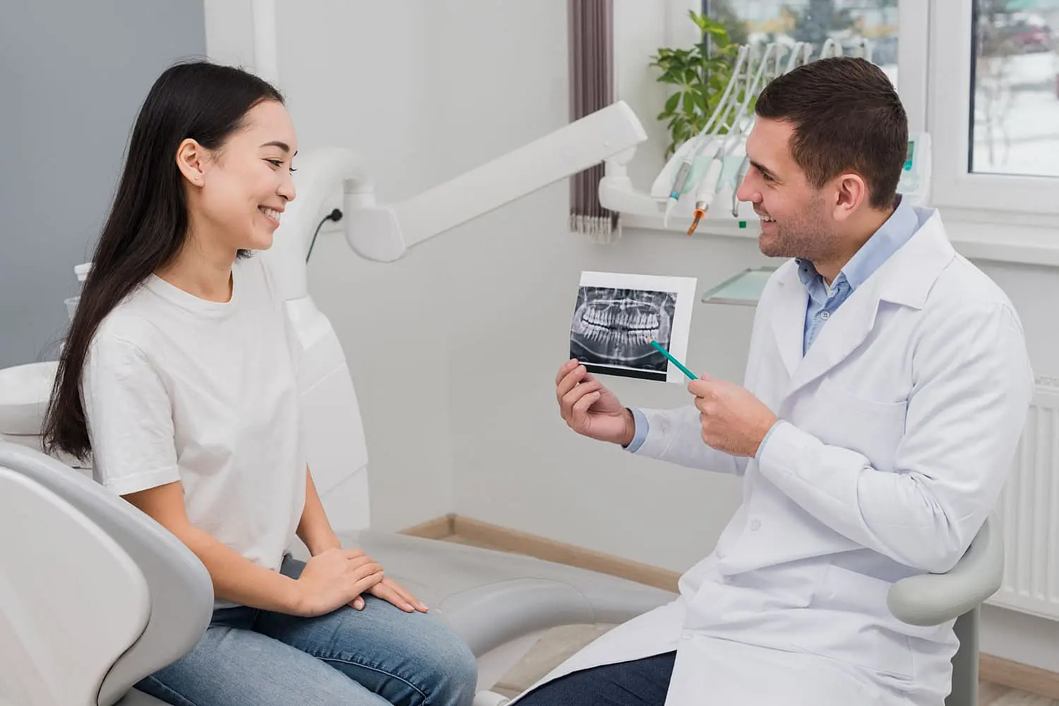 The dentist at Chauncey Orthodontics in Henderson NV, discusses a dental X-ray with a female patient, emphasizing the benefits of an Invisalign payment plan to enhance her smile.