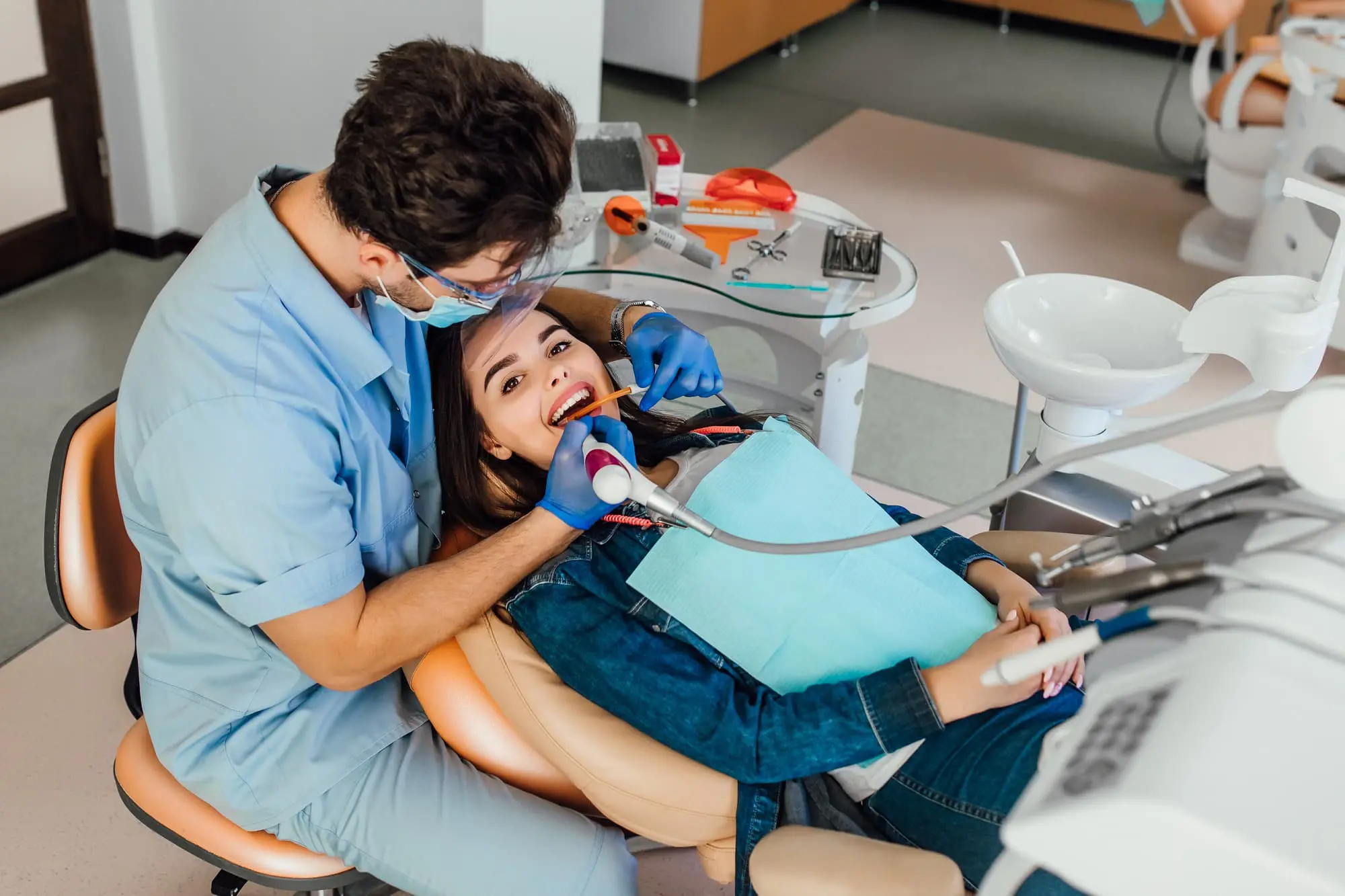 In a modern dental office, a professional at Chauncey Orthodontics operates in Henderson NV, examines a patient's teeth for signs of tongue thrust while wearing gloves and a mask.