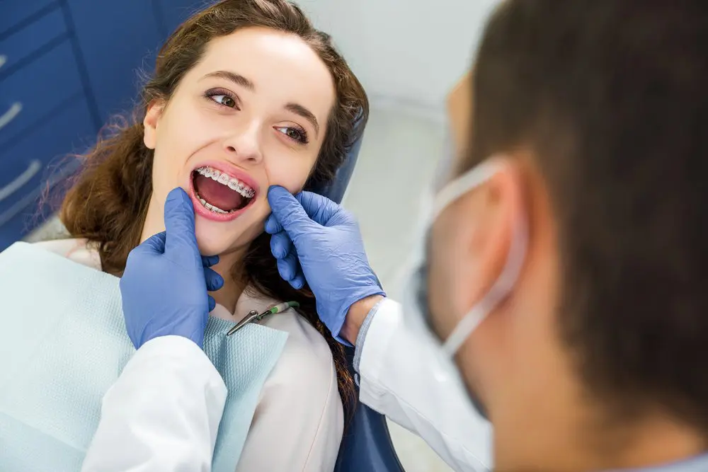 A dentist wearing gloves examines a young woman’s teeth and metal braces during a dental appointment at Chauncey Orthodontics in Henderson, NV.