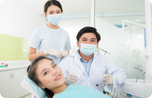 A dentist and dental assistant wearing masks and gloves attend to a patient with metal braces who is lying on a dental chair in a clinic at Chauncey Orthodontics in Henderson, NV.