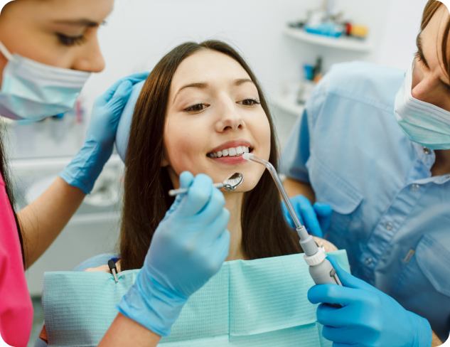 A woman is sitting in a dental chair, receiving treatment adult orthodontics from two dental professionals wearing masks and gloves in Henderson, NV.