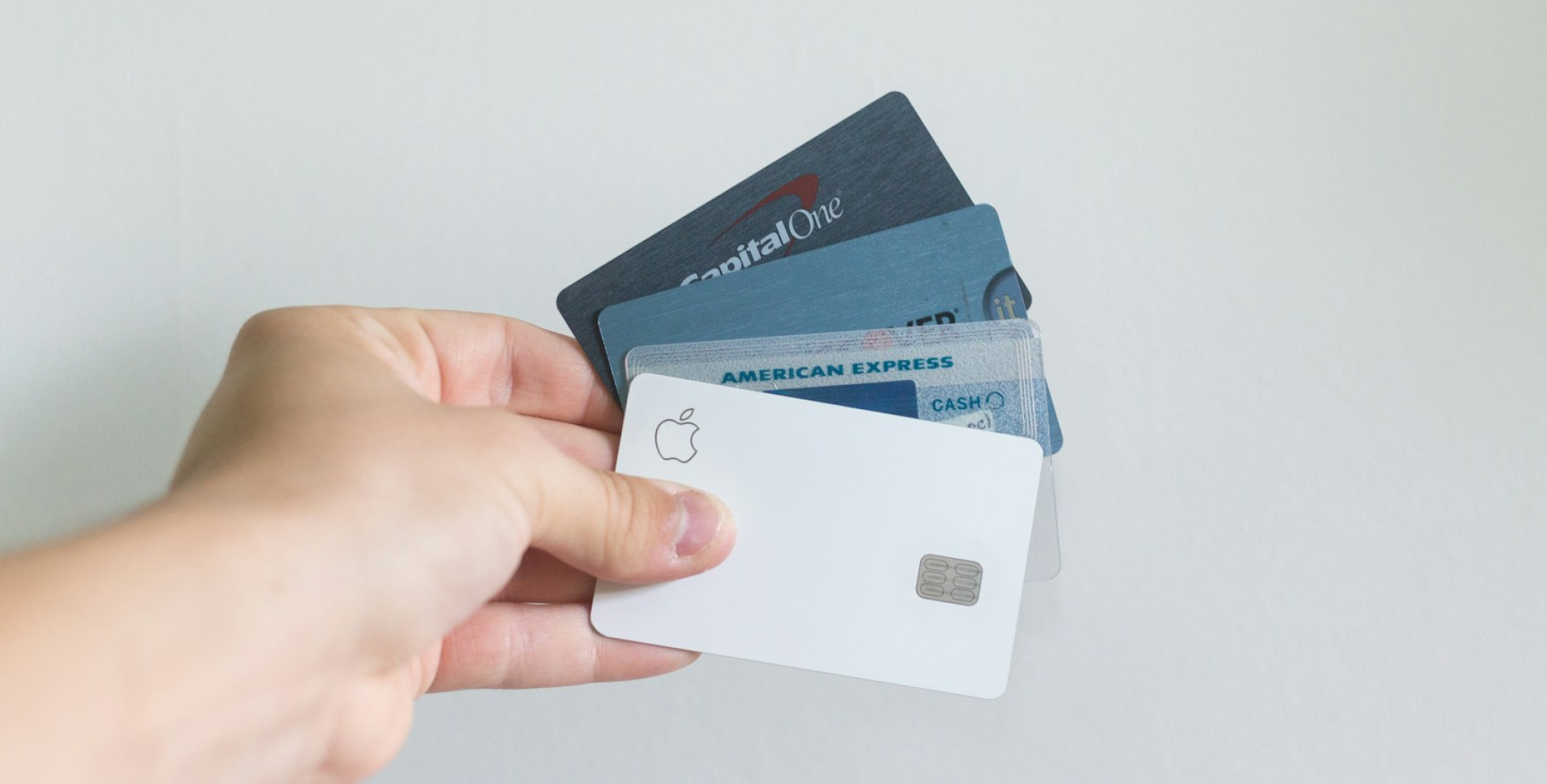 A hand showcases a variety of credit cards, including Apple Card, American Express, and Capital One, perfectly fanned out against a plain background—ready for any purchase, even your Invisalign payment plan at Chauncey Orthodontics operates in Henderson, NV.