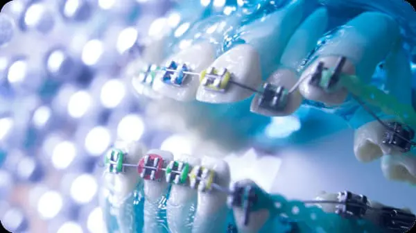 At Chauncey Orthodontics in Henderson NV, a dentist wearing gloves and a mask examines a smiling patient with metal braces in the dental chair.